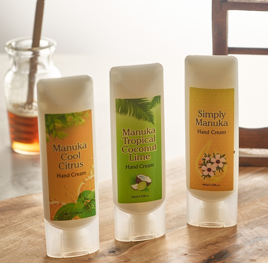Three Manuka honey hand cream tubes, citrus, coconut lime, and floral scents on a table.