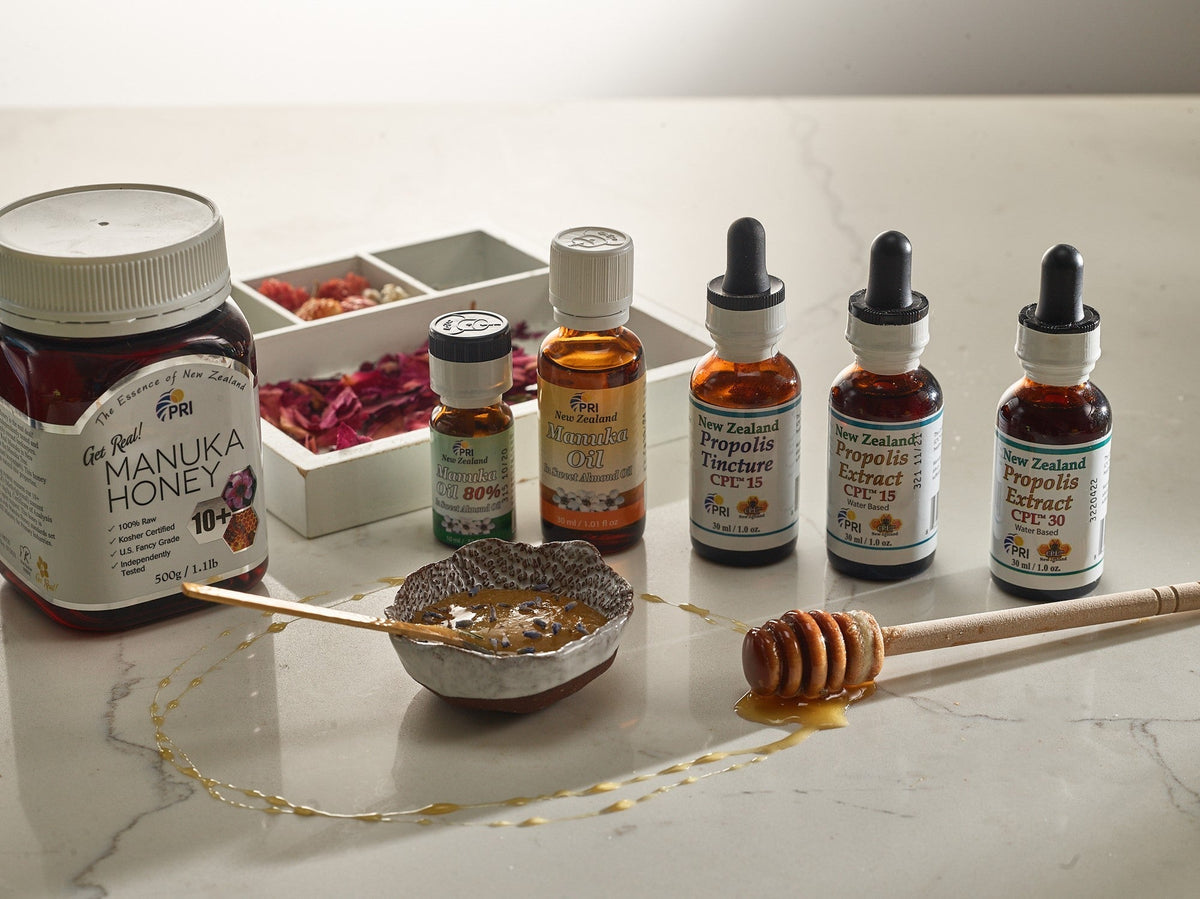 Manuka honey jar with essential oils and propolis extract bottles on a marble countertop