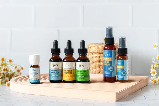 Group display of Manuka oil, propolis extract, and oral throat sprays on wooden tray