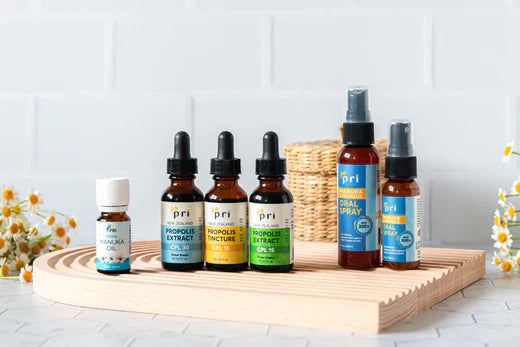 Group display of Manuka oil, propolis extract, and oral throat sprays on wooden tray