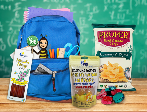 Blue backpack with school supplies, Manuka honey snacks, crisps, and candy on desk